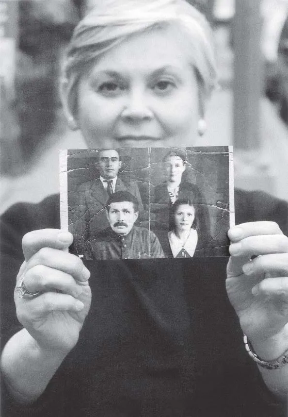 Esther Safran Foer holds up a tattered black and white photograph of her father, Louis Safran, an older man, and two women.