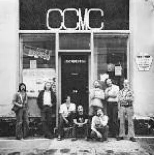 Members in front of a store front that has the letters “CCMC” in a skinny font of the awning of the building. Some are standing while others sit on the front steps.