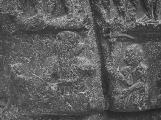 Figure 1.2 Detail of a victory stele of Sargon, showing the king holding a battle net, a gash from later vandalism, a label reading “King Sargon,” and an attendant carrying a sunshade.