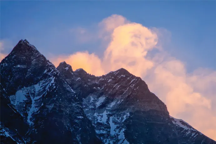 15.1 Alpenglow lights up luminous plumes of icy spindrift blown from the peak of Mt. Everest in the pre-dawn twilight.