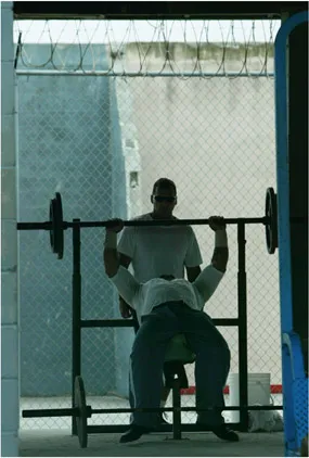 FIGURE 1.1 An inmate lifts weights at the Hendry Correctional Institution in Immokalee, Florida. Physical fitness programs and equipment in prisons have been labeled as “frills” by some who argue that inmates should fare no better than the least advantaged individuals in society. Credit: AP photo/Wilfredo Lee