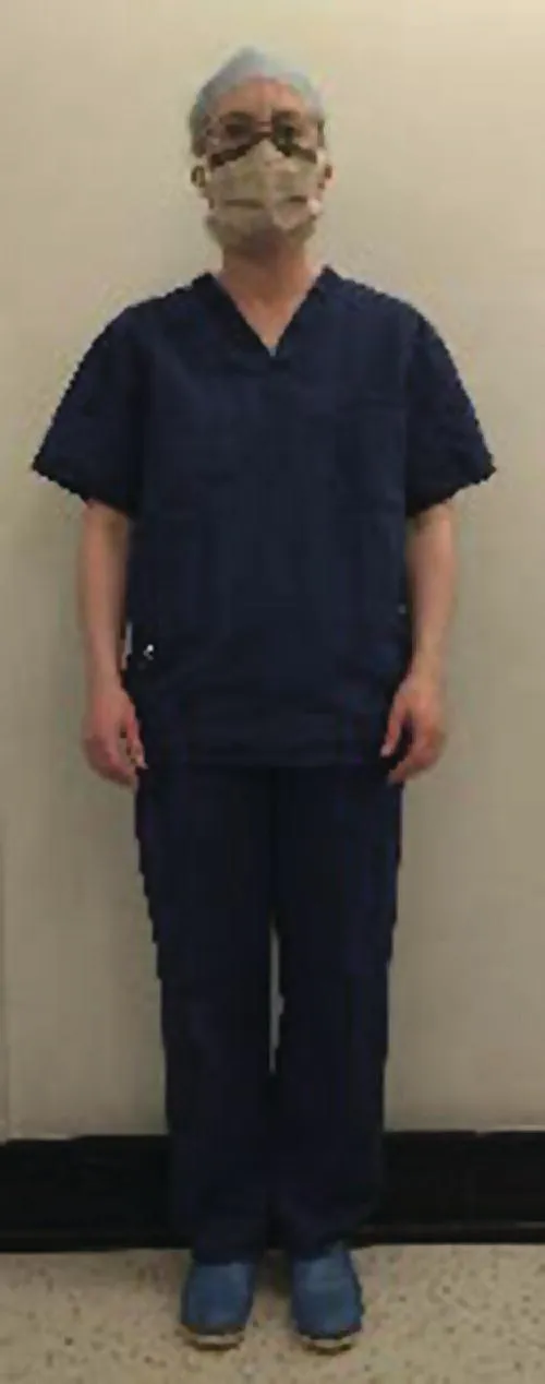 Photo displaying a standing medical staff wearing scrub suit, a hat, a pair of protective eye goggles, and a mask.