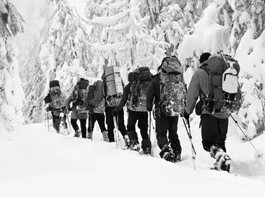 Fotografía de un grupo de alpinistas en fila india, caminando por la nieve.