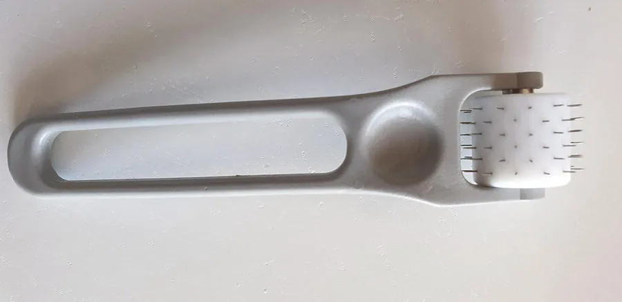 Photo depicts an original microneedling roller created by Dr. Desmond Fernandes in 2001. The fixed needle length of 3.0 mm multiuse roller; designed for reuse on a single patient for approximately six treatment sessions.