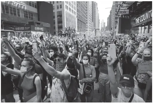 People protest the brutal police killing of George Floyd in 2020 in a city, with their arms outstretched.