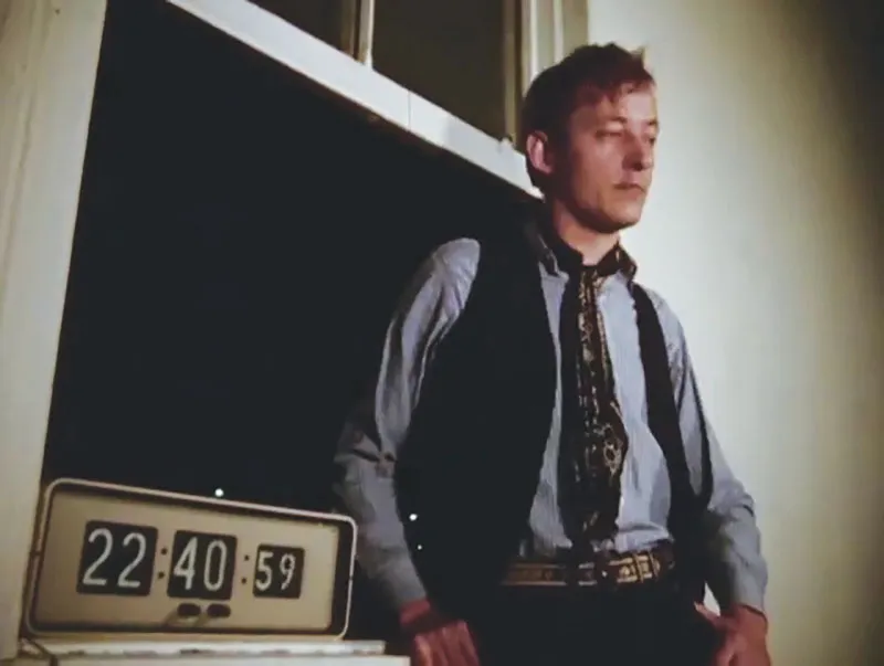 The film still shows a man by the window, with an alarm clock on the windowsill.