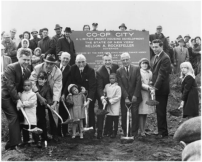 Figure 2. A group of people stand around a sign that says “Co-Op City.” Men in suits and small children are lined up at the front. Eight people in this front line have shovels full of dirt and are participating in the groundbreaking ceremony.