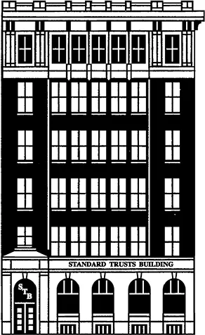 A six-storey building with the top and bottom storeys divided by pediments and in a different lighter material. The entrance to the building is on the left and a sign above the ground floor reads “Standard Trusts Building.”