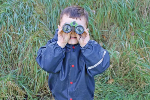 One child looking at the camera through binoculars.