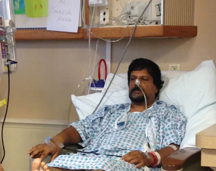 Author in hospital gown after cancer surgery, connected to monitors and intravenous tubes.