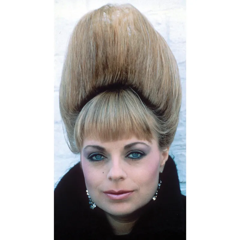 Un esempio delle voluminose acconciature degli anni Ottanta, una strategia per aumentare l’altezza. A differenza delle alte parrucche dei secoli scorsi, questa pettinatura si ottiene cotonando i capelli della donna e laccandoli  fino a trasformarli in una rigida torre. © Rex Features/Still Press Agency