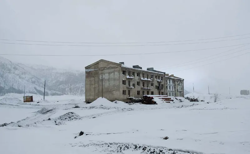 «Il camion rallenta un po’ e noi ci avviciniamo alla periferia di Susuman. Un paio di edifici di cemento, territori abbandonati, vecchie case e qualche macchina arrugginita coperta da cumuli di neve.»