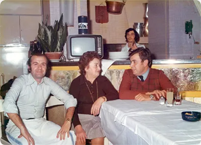 Vittorio e Giorgio Urbani con la mamma Santina seduti al tavolo “comune” del loro ristorante.