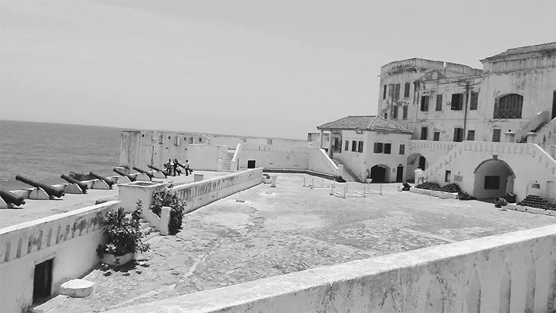 Il castello di Cape Coast. I cannoni sulla sinistra sono posti al di sopra del corridoio che dalle segrete conduceva i prigionieri verso le chiatte dirette alle navi. Il piccolo edificio con il tetto in tegole, sulla destra al centro, era la cappella, costruita sopra le celle degli schiavi.