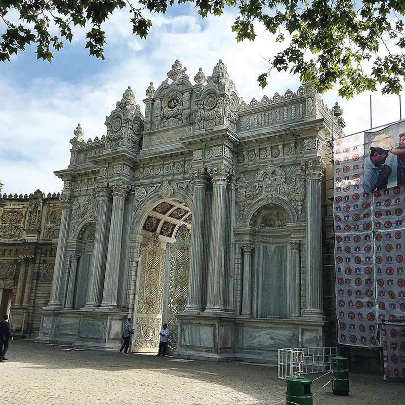 16. Il monumentale ingresso al palazzo reale di Dolmabahçe, sulla riva europea del Bosforo, inaugurato nel 1856. L’arrivo piú spettacolare è per via d’acqua avendo di fronte i seicento metri (!) di facciata di uno dei piú sontuosi edifici mai concepiti, fiancheggiato da giardini lussureggianti perfettamente tenuti. La sua costruzione costò l’equivalente di trentacinque tonnellate di monete d’oro. Solo per le sfavillanti decorazioni in foglia d’oro di alcuni soffitti ne furono utilizzate quattordici tonnellate; la superficie della parte ufficiale ha un’estensione di 45 000 metri quadrati: 44 sale, 285 stanze. Lo stile riprende alcune forme dell’architettura ottocentesca europea piegata al disegno e allo sfarzo orientali.