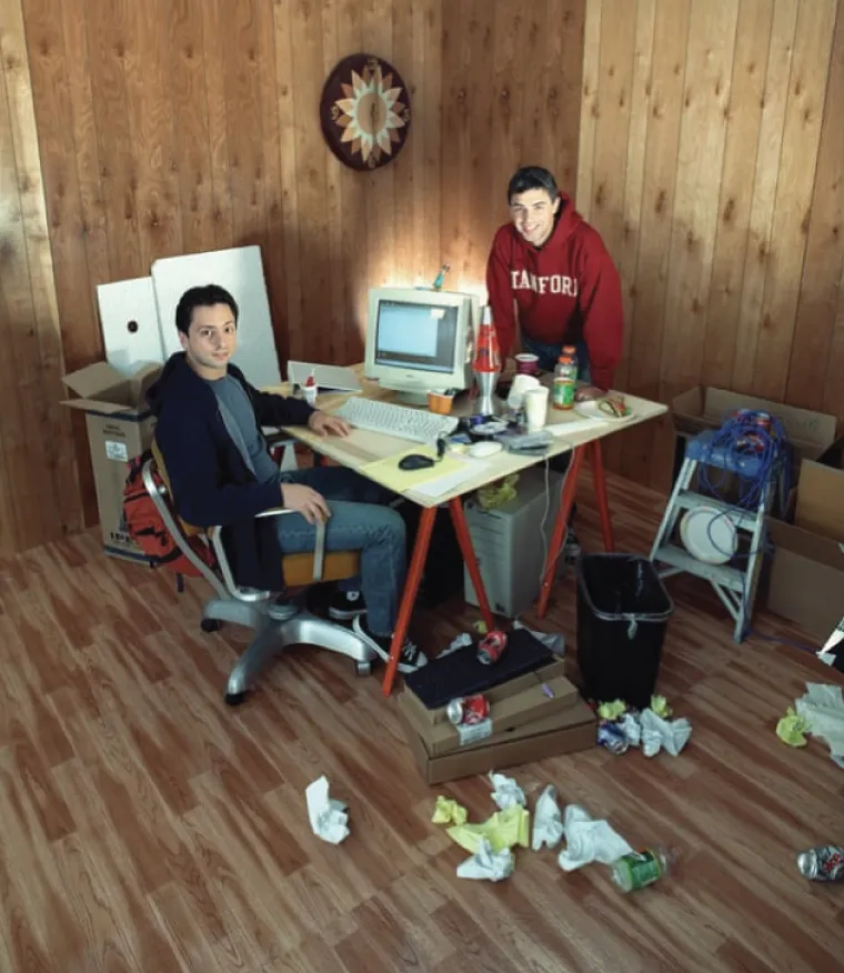 Photo depicts Sergey Brin, left, and Larry Page posing in a messy office setting in October 2002