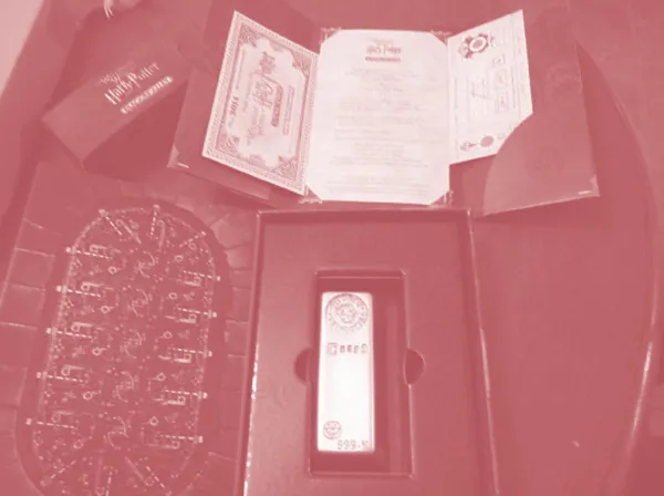 An open fancy box and beside it the park invitation including a Hogwarts train ticket and wristband