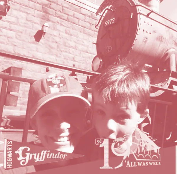 Erin grins beside her young son with the Hogwarts Express train in the background.