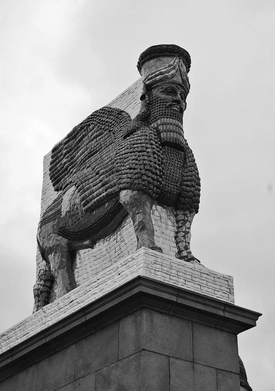 Sculpture of the lamassu on a plinth with the title “The Invisible Enemy Should Not Exist.”