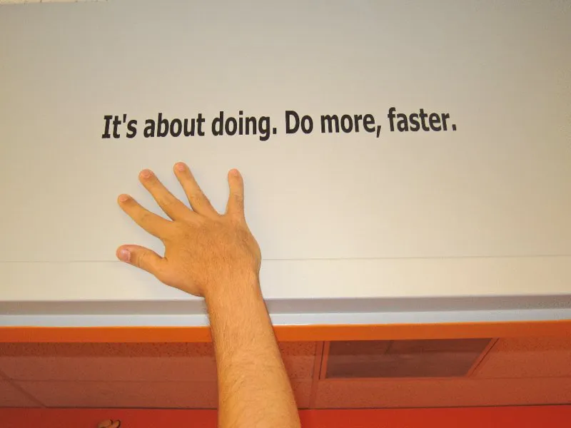 Image of a hand and forearm flat on a table, fingers spread wide. At the top is the text “It’s about doing. Do more, faster.”