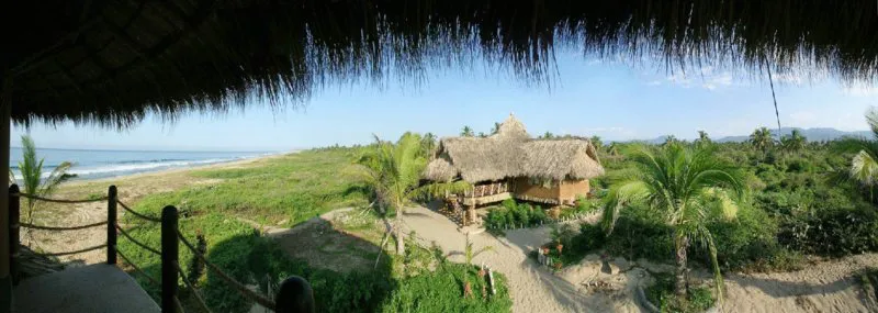 Photograph: resort having casitas surrounded by trees in front of beach.